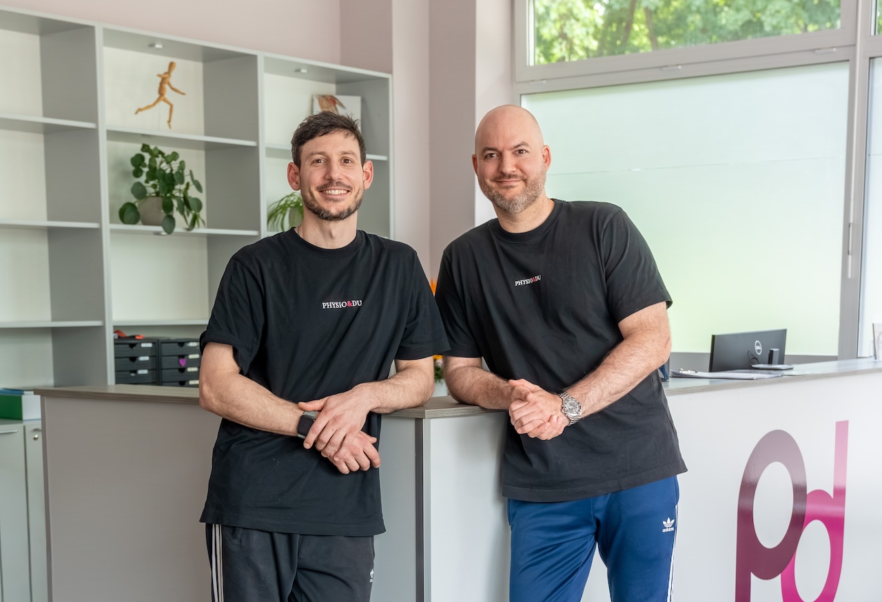 Alexis Poltermann und Cimon Ardame am Empfang der Praxis physio&du